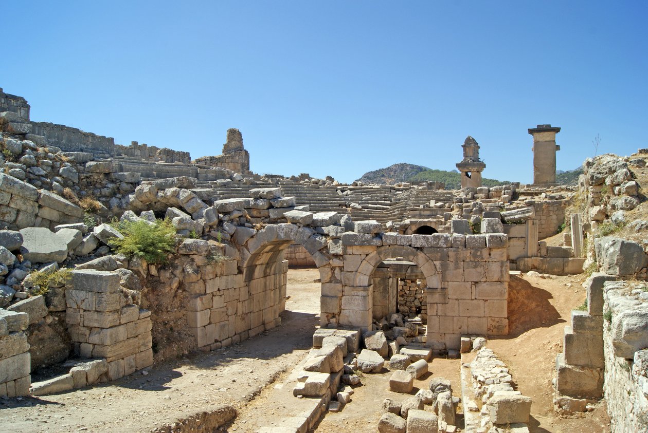 Pohled přes klenutý vchod divadla Xanthos do jámy orchestru, zobrazující sloup a hrobku Harpyje, Xanthos, Turecko (foto) od Roman