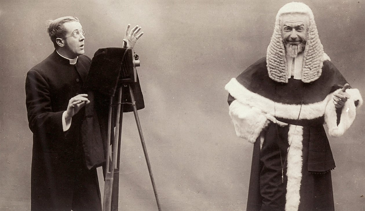 Muž v sutaně míří objektivem svého fotoaparátu na muže oblečeného jako papež od Rotary Photographic Co Ltd