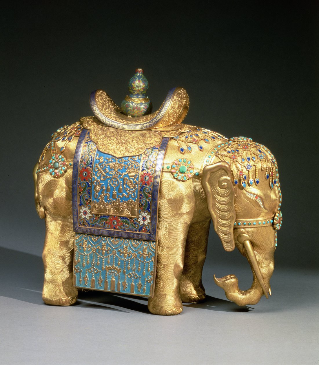 Postava slona se smaltovanými ozdobami a korálovými a tyrkysovými kabošony, sedlovka zdobená buddhistickými emblémy, období Chien Lung, kolem roku 1780 (zlacený bronz, smalt, korál a tyrkys) od School Chinese