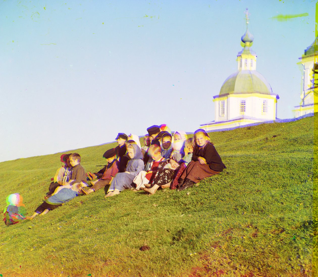 Ruské děti sedící na úbočí kopce poblíž kostela a zvonice na venkově poblíž Bílého jezera, na severu evropského Ruska, 1905-1915 od Sergey Prokudin Gorsky