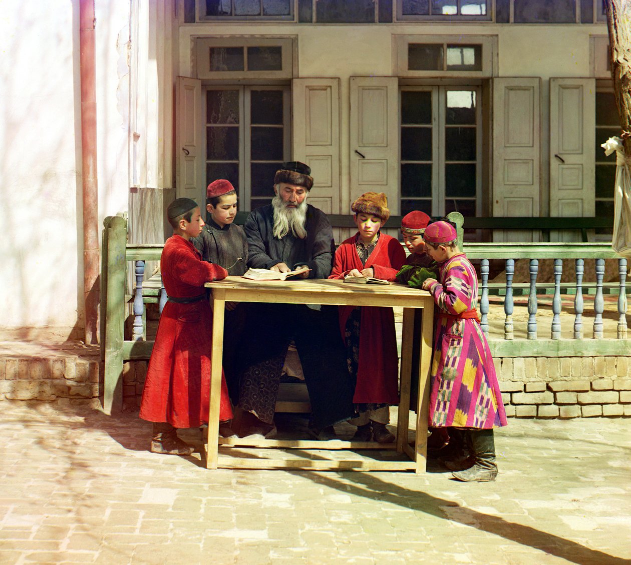 Skupina židovských dětí s učitelem na stole před domem, Samarkand, Ruská říše, mezi lety 1905 a 1915 od Sergey Prokudin Gorsky