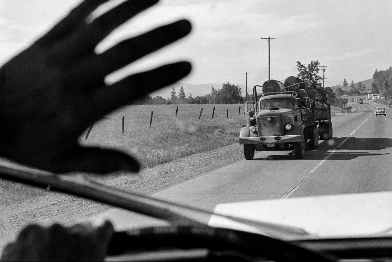 Řidič nákladního auta na těžbu dřeva mává na jiné nákladní auto na těžbu dřeva. od Ted Spiegel