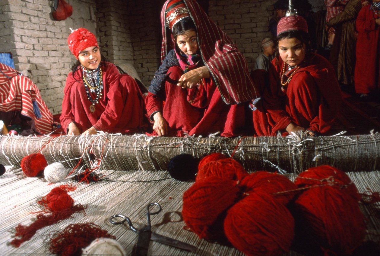 Tkalci a tkalkyně turkmenského kmene upravují uzly na osnově koberce na tkalcovském stavu ve vesnici... od Thomas J. Abercrombie