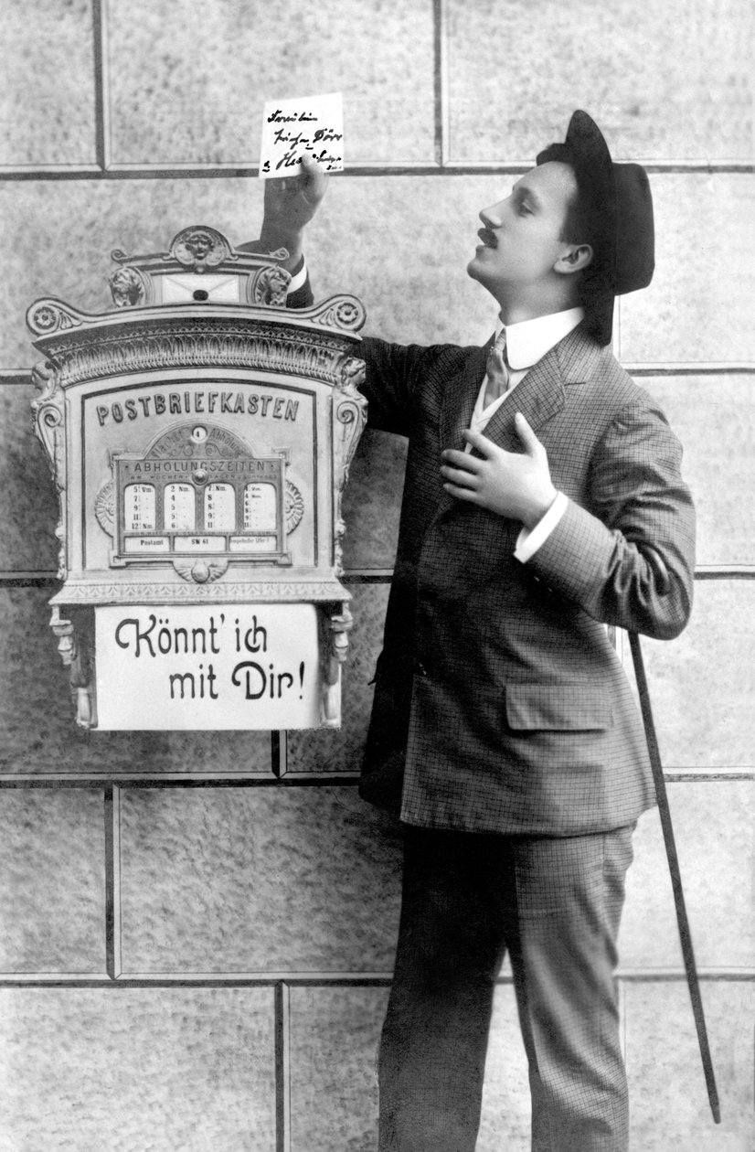 Elegantní muž v obleku, klobouku a hůlce posílá vzkaz do poštovní schránky. Německo kolem roku 1920 Historická fotografie, muž vedle poštovní schránky, kolem roku 1920 od Unbekannt