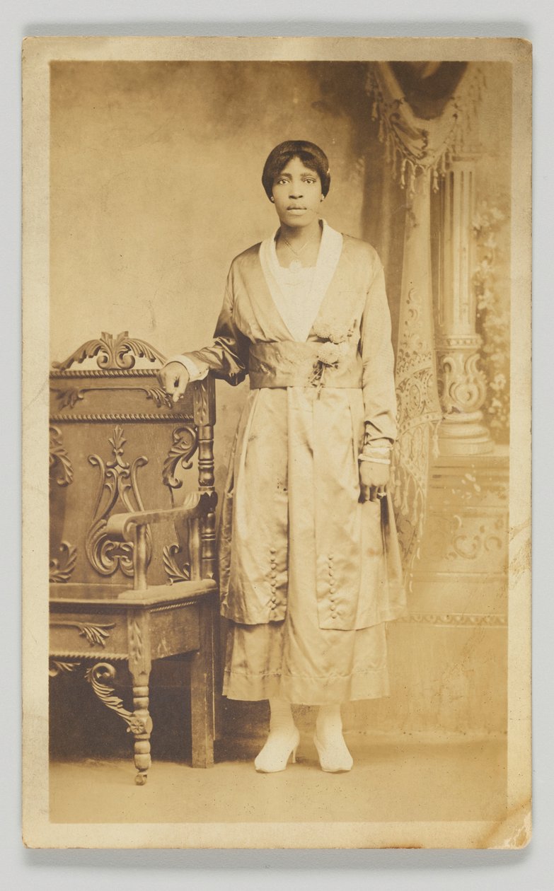 Fotografická pohlednice ženy stojící vedle dřevěné židle, 1904-1918. od Unbekannt