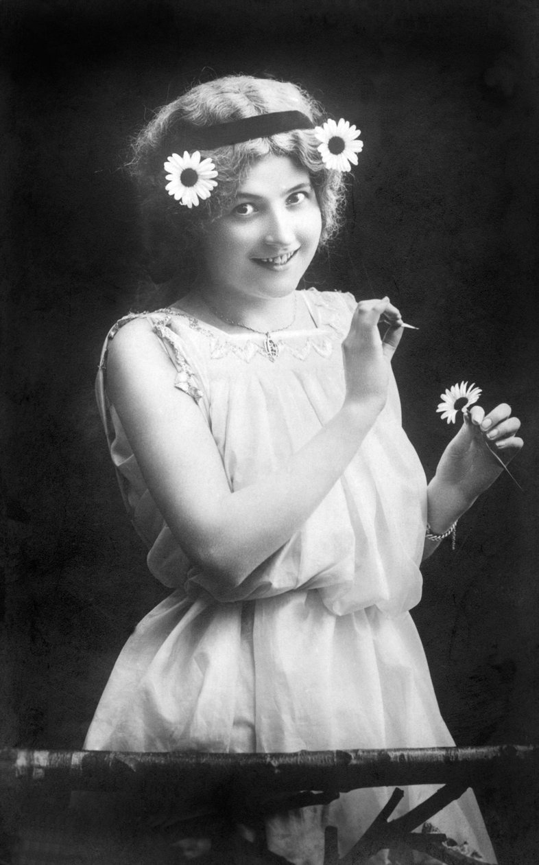 Žena vytahující okvětní lístky z květiny: „“ Miluje mě. Nemá mě rád. Miluje mě...“ Fotografie kolem roku 1912 od Unbekannt