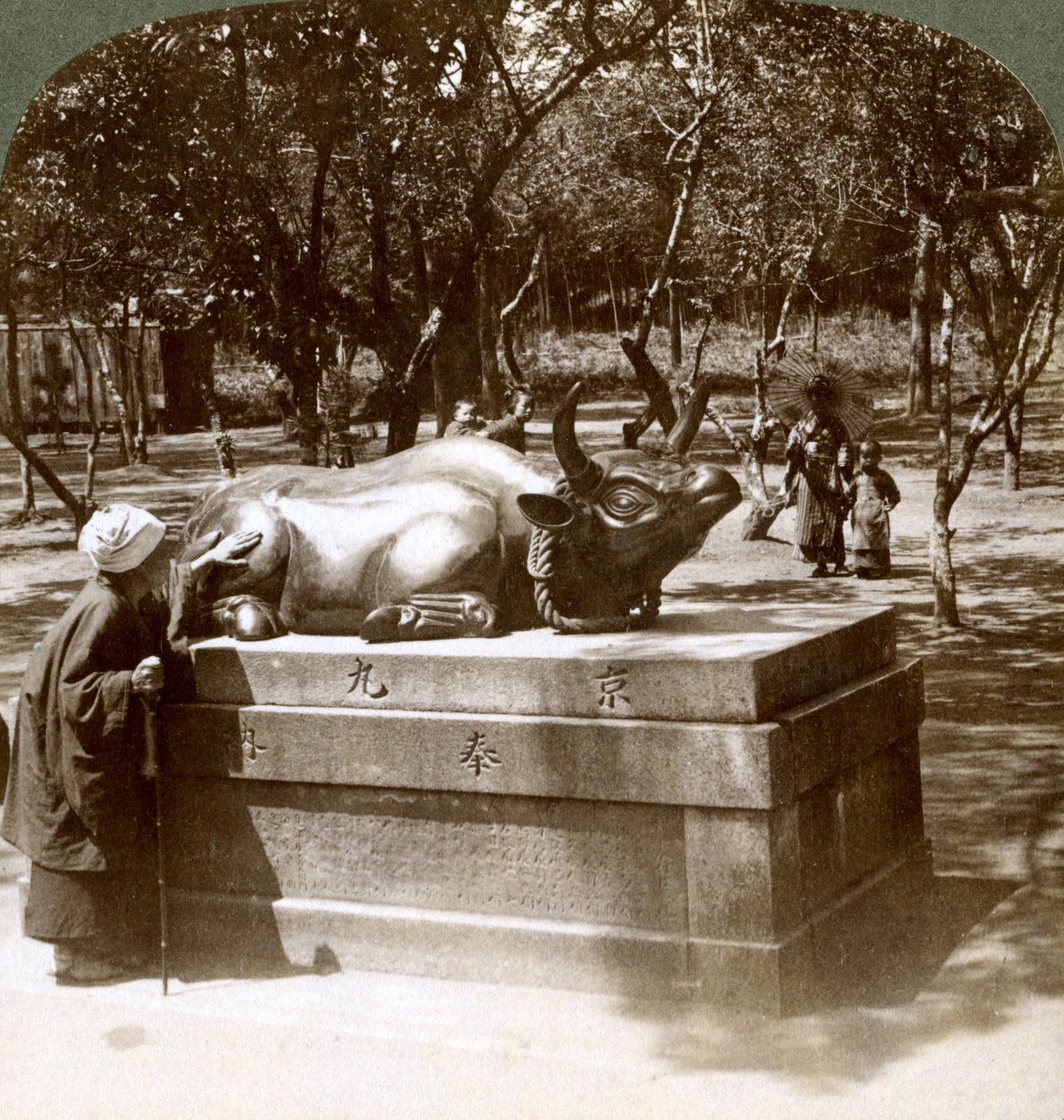 Zbožná žena hladící bronzového býka k léčbě revmatismu, chrám Kitano Tenjin, Kyoto, Japonsko, 1904 od Underwood and Underwood