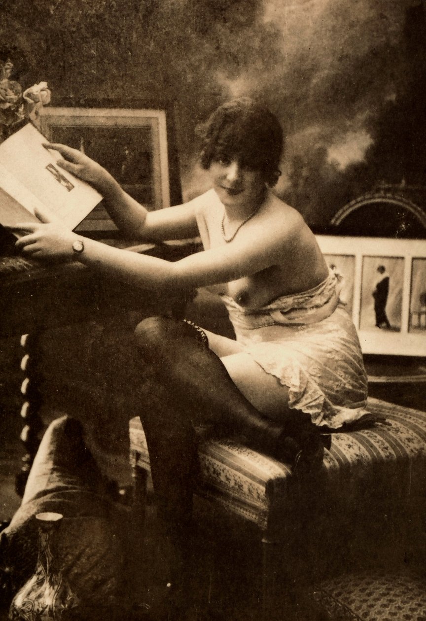 Portrét mladé ženy v intimním oděvu, sedící u stolu s knihou. od Unknown photographer