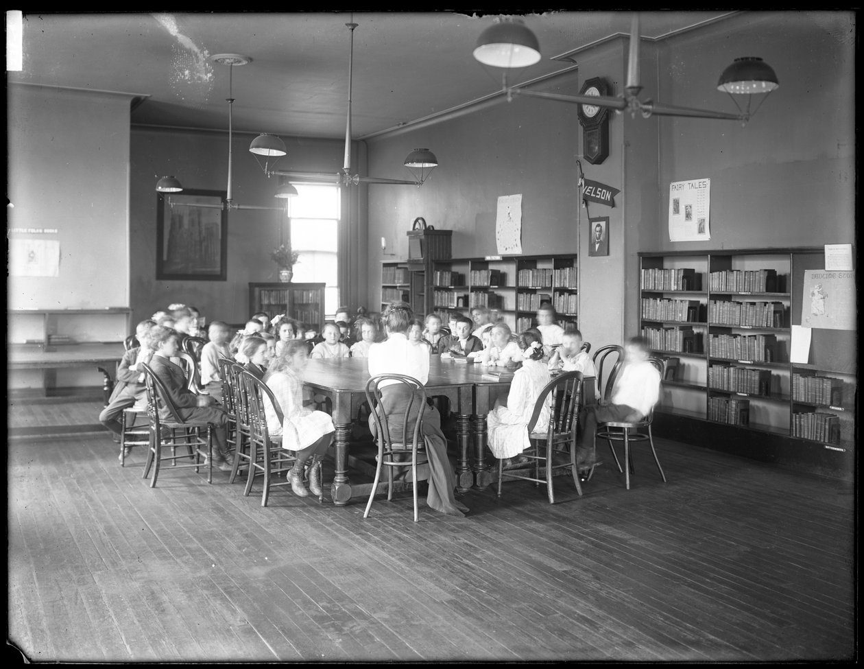 Děti poslouchají ženu v čítárně neidentifikované pobočky veřejné knihovny Queens Borough, kolem roku 1910 (černobílá fotografie) od William Davis Hassler
