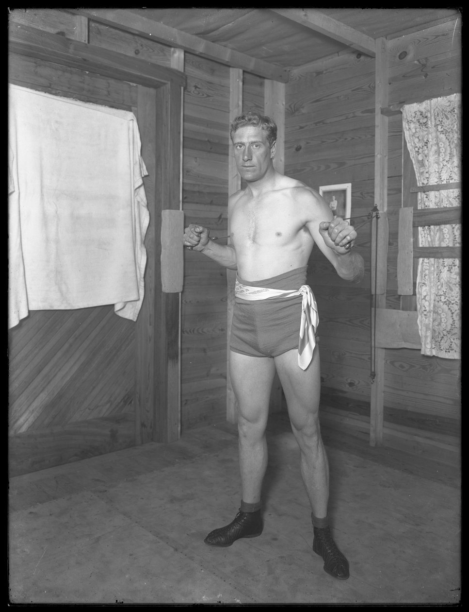 Anglický boxer William Thomas Wells (Bombardier Billy Wells), pózující v tréninkových taškách s kladkami, kolem roku 1911 od William Davis Hassler