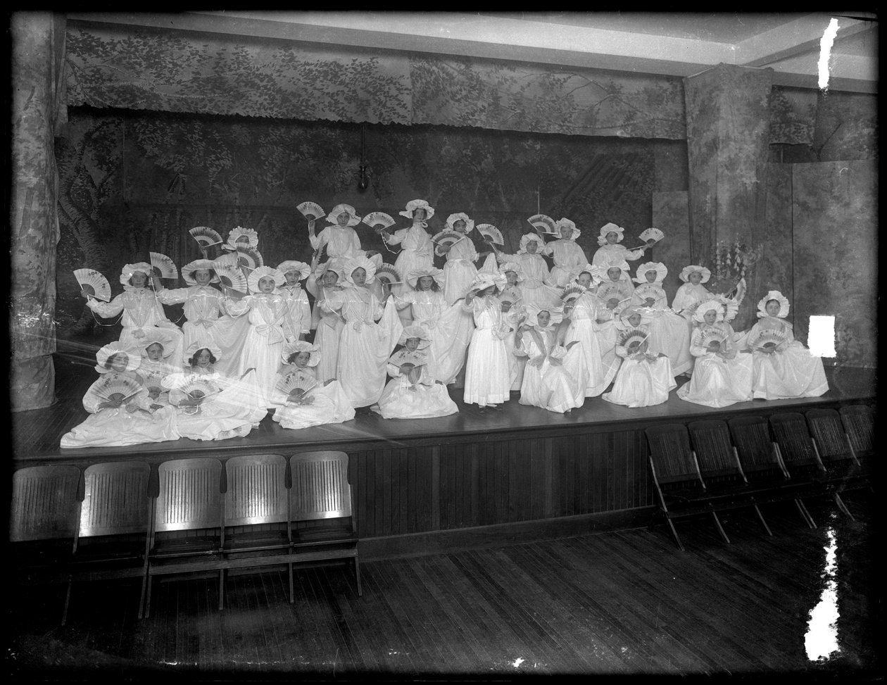 Skupina malých dívek pózovala na malém pódiu s fanoušky, pravděpodobně římskokatolický sirotčí azyl, Kingsbridge, Bronx, kolem roku 1911 od William Davis Hassler