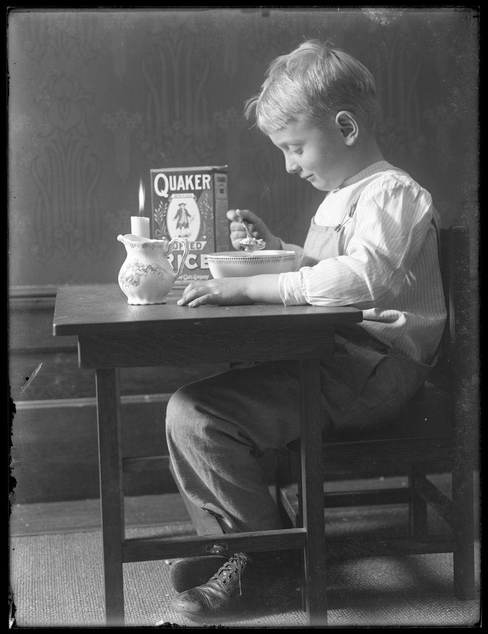 William Gray Hassler sedí u malého stolku a jí misku rýžových lupínků Quaker, asi 1912 od William Davis Hassler