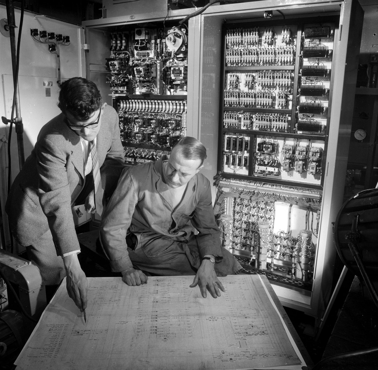 Inženýři diskutují o plánech před elektronickým ovládacím panelem, který postavili od Frederick (attr. to) Barnard