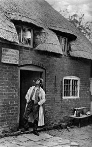 Muž kouří dýmku před obchodem, Worcestershire, c1922. od A. W. Cutler