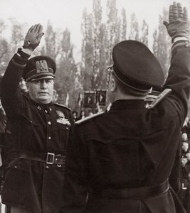 Benito Mussolini ctí fašistického úředníka pozdravem (černobílá fotografie)