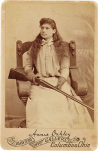 Annie Oakley: Annie Oakley:. Legendární ostrostřelec zde sedí poněkud zdrženlivě v masivním křesle v renesančním stylu a brokovnici spočívající v jejím klíně. Její jemné ženské rysy a vlající vlasy Belie Her Rugged Outdoors Obrázek ©Buyenlarge/UIG/Leemage od American Photographer