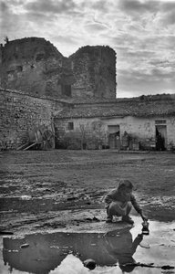 Mladá dívka si hraje s papírovou lodičkou v kaluži obklopené bahnem, Venosa, Basilicata, Itálie