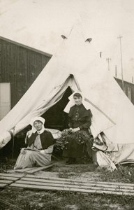 Sestra Eleanor Wibmer Jeffries a sestra Nellie Constance Morrice (vpravo) před svým stanem v australské všeobecné nemocnici č. 3 s květinami natrhanými z břehu řeky Somme, c. června 1917 (černobílá fotografie od Australian Photographer