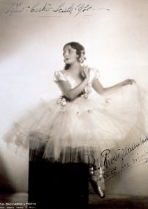 Portrét klasické baleríny Rosy Piovella Ansaldo v tutu a baletních botách. Sedí vpředu, obličej otočený na jednu stranu. Látkové růže zdobí její oděv a pečlivě upravené vlasy (Milán, Teatro alla Scala) (č/b foto) od Baccarini and Porta