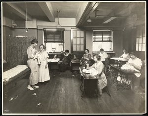 Slepé mladé ženy a učitelka šijící ve třídě v New York Association for the Blind, 111 East 59th Street, New York, 1921 (stříbrný želatinový tisk)