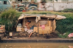 Kartonová chatrč podél odpadního kanálu slouží jako domov. Jakarta, Indonésie.