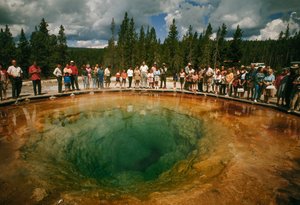Návštěvníci parku se shromažďují kolem modrozeleného termálního bazénu ve tvaru květu. Yellowstonská přírodní rezervace...