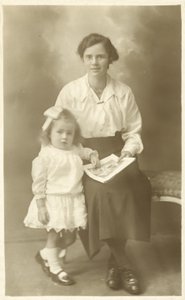 Hezká dívka, matka nebo vychovatelka, ukazuje fotky malému dítěti (černobílá fotografie) od English Photographer