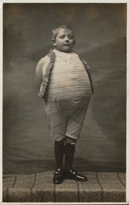 Školák, oblečený tak, aby měl velmi velké břicho (černobílá fotografie) od English Photographer