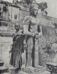 Mladý buddhistický novicový mnich vedle sochy Buddhy, Francouzská Indočína (černobílá fotografie)