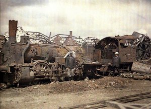 Vyhořelá lokomotiva a železniční vůz před ruinami těžce poškozeného lihovaru Vauxrot, Cuffies, Aisne, Francie, 1917 (autochrom)