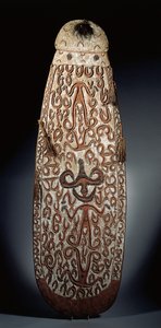 Oválný štít Asmat, vyřezávaný v reliéfu s rolovacím ornamentem zahrnujícím vysoce stylizované postavy, spletené střapce k okraji (dřevo, rafie a peří) od Guinean New