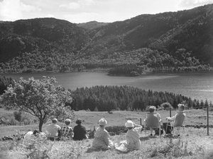 Skupina lidí sedících na trávě nebo lehátkách a hledících na výhled na Thirlmere od Joseph Hardman