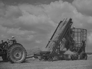 Traktor táhnoucí pojízdný rám a nakládání sena do něj od Joseph Hardman
