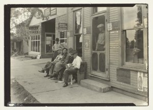 Muži se psem sedící na lavičce před obchodem General Store od Lewis Wickes Hine