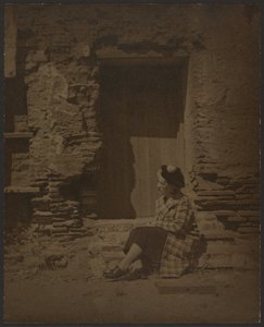 [Žena sedící před chátrající budovou] od Louis Fleckenstein