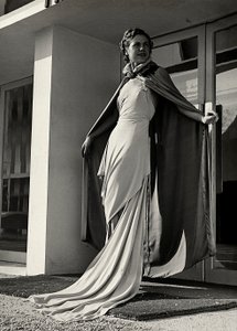 Model ve večerních šatech vytvořený couture house "Graldi". Článek je doplněn pláštěm z lehké tkaniny. (černobílá fotografie)