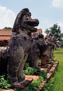 Kamenné postavy strážců připomínající lva postavené kolem základny stúpy od Thai School