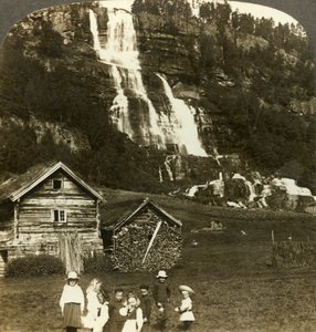 Děti si hrají na farmářském poli s terasovitým vodopádem Tvinde, Vossevangen, Norsko, c1905. od Unbekannt