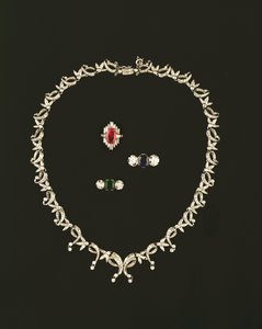 Náhrdelník ve stylu art deco se svitkem a listem; prsten s rubínovou a diamantovou bagetou; safír a diamantový prsten se třemi kameny; smaragdový a diamantový prsten se třemi kameny