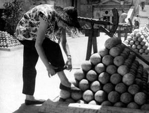 Žena si upravuje manžetu u kalhot a opírá si nohu o hromadu dělových koulí v areálu Andělského hradu v Římě. od Unknown photographer