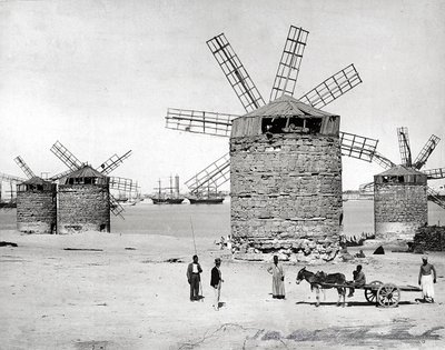 Větrné mlýny na Středozemním moři v Alexandrii v Egyptě. Vpředu pózuje několik Egypťanů s malým vozíkem od Brothers Zangaki