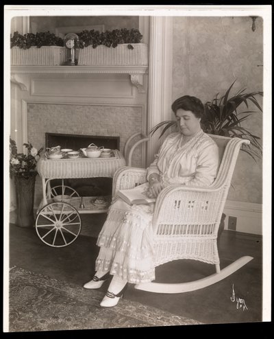 Paní Howardová seděla s knihou v houpacím křesle ve svém domě na 200, 5th Avenue, New York, 1915-6 (stříbrný želatinový tisk) od Byron Company