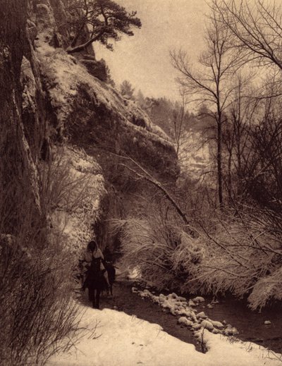 Míjení útesu, zimní scéna. Indiáni Apsaroke na koni podél útesu ve sněhu na řece Pryor v Montaně. Fotografie převzata ze svazku 4 encyklopedie vydané Edwardem S. Curtisem (1868-1952) o Indiánech Severní Ameriky, s předmluvou Theo od Edward Sheriff Curtis