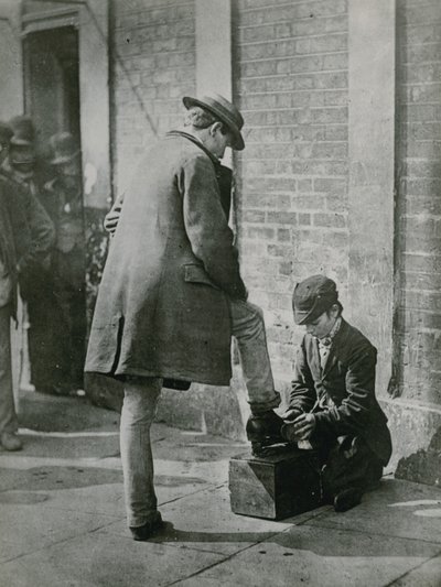 Mladý obuvník leští na ulici pánské boty od English Photographer