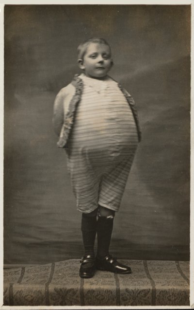 Školák, oblečený tak, aby měl velmi velké břicho (černobílá fotografie) od English Photographer