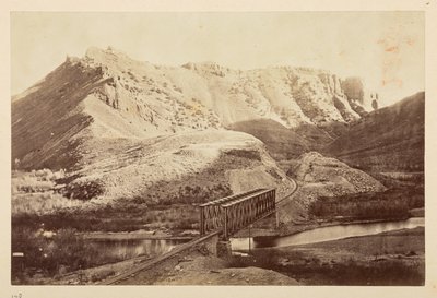 Pohledy na Pacifickou železnici, železniční trať překračující řeku po trámovém mostě s horami za nimi od English Photographer