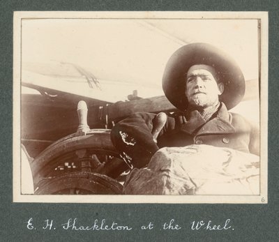 E. H. Shackleton stojí u kormidla lodi Discovery (1901) Z alba sira Ernesta Henryho Shackletona s názvem Národní antarktická expedice (1901-1903) od Ernest Henry Shackleton