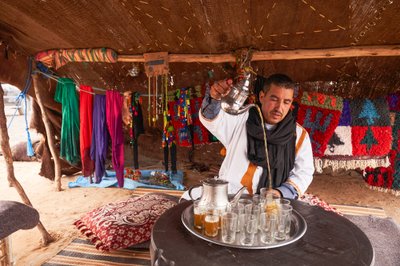 Místní obyvatel podává mátový čaj v poušti Erg Chebbi nedaleko Merzougy, Maroko, 2019 (foto) od Ira Block