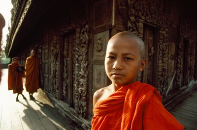 Mladý začínající mnich před vyřezávanými teakovými deskami. Klášter Shwenandaw, Mandalaj, Barma. od James L Stanfield