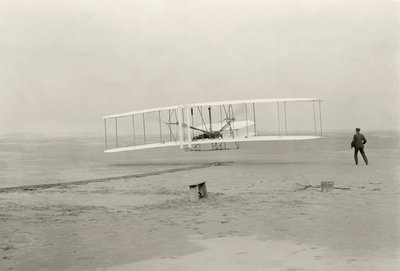 Wright Flyer I uskutečnil svůj první let z výšky 120 stop za 12 sekund v Kitty Hawk v Severní Karolíně. od John T. Daniels